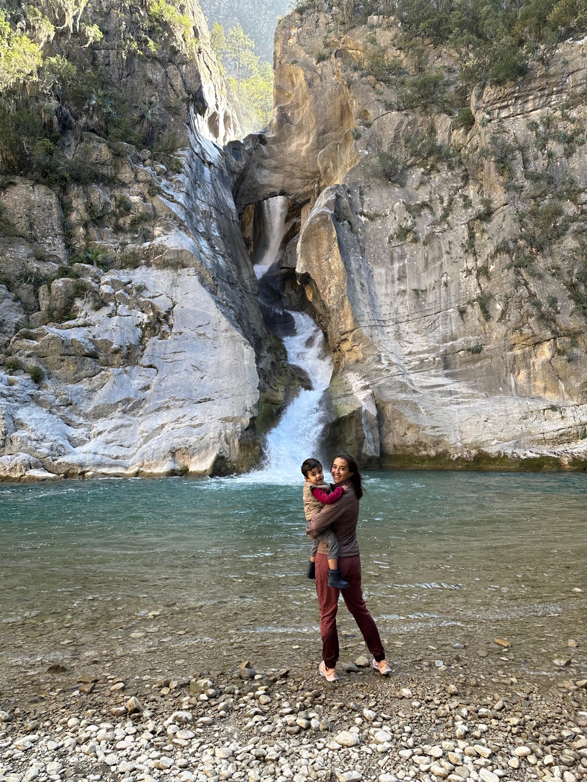 Ana, fundadora de Hike Like A Mom, con su hijo Elian frente a una cascada